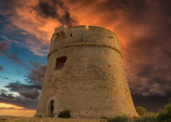 Low angle view of old tower against sky during sunset