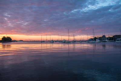 Silhouette sailboats in sea against sky during sunset