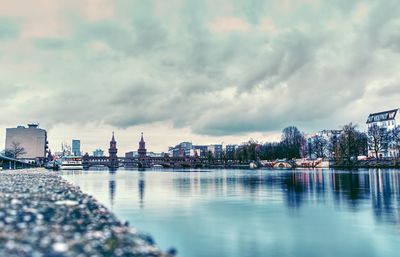 City at waterfront against cloudy sky