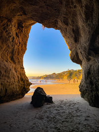 Rock formation on beach against sky during sunset