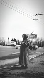 Man on street against sky in city