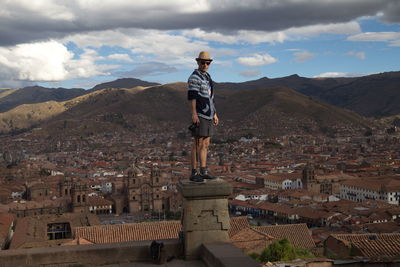 Man standing at observation point over cityscape against sky