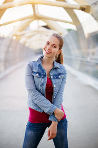 Portrait of smiling young woman standing on bridge