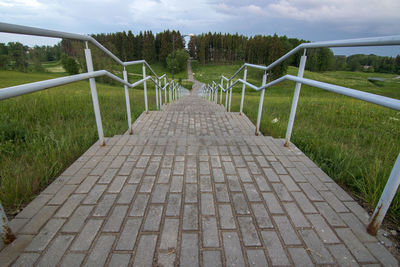 Footpath by railing against sky