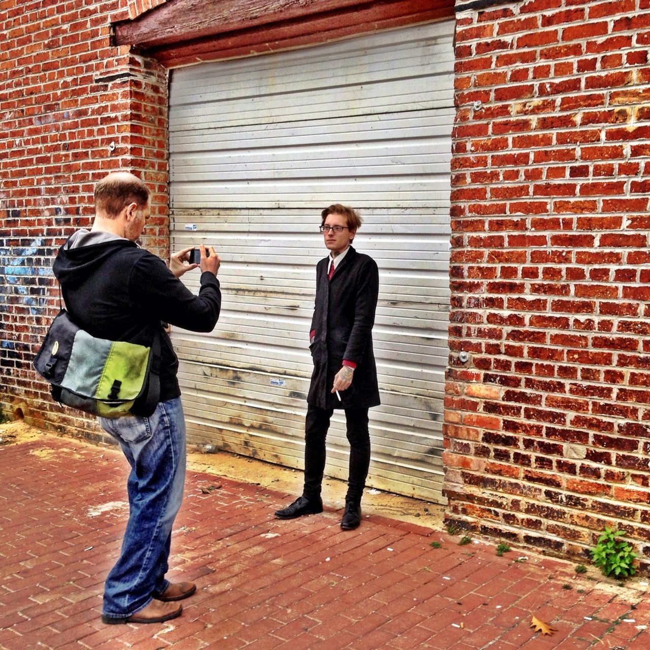 casual clothing, lifestyles, full length, built structure, architecture, building exterior, standing, young adult, leisure activity, brick wall, person, young men, wall - building feature, front view, hands in pockets, looking at camera, portrait