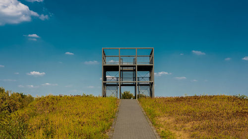 Footpath amidst field against sky