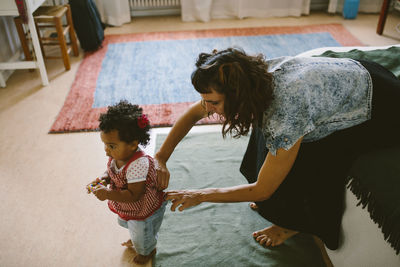 Mother adjusting clothes of daughter standing at home