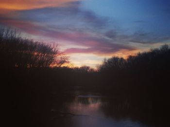 Silhouette trees by lake against sky during sunset