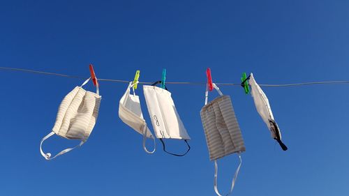 Low angle view of clothes hanging on clothesline against blue sky