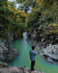 Man standing on rock by river