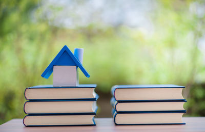 Stack of books with home model on table at home