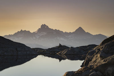 Scenic view of lake and mountains against sky during sunset