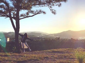 Woman standing by tree against sky