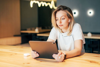 Young woman using mobile phone while sitting on table