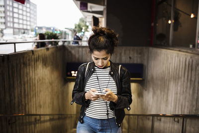 Woman using smart phone while walking at subway station