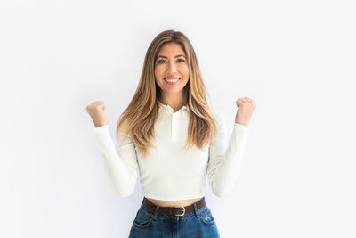 Portrait of young woman standing against white background