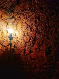 Low angle view of illuminated light bulb on wall