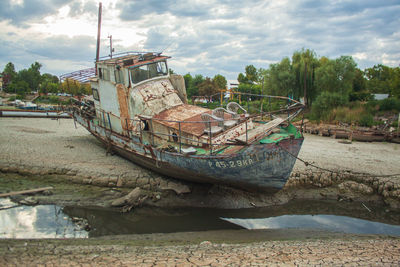 Abandoned boats moored on shore against sky