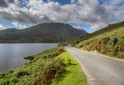 Road amidst green mountains against sky