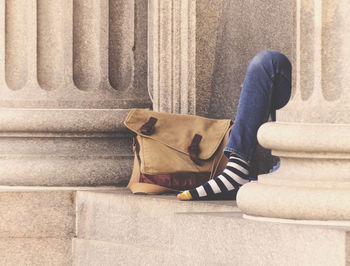 Low section of woman with bag by column