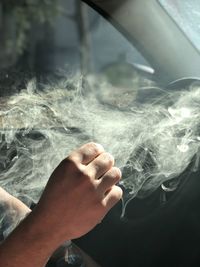Cropped hand of person smoking in car