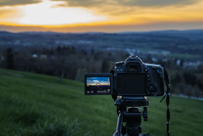 Camera on field against sky during sunset