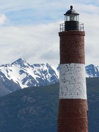 Lighthouse on snow covered mountain against sky