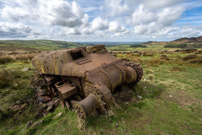 Abandoned car on field against sky