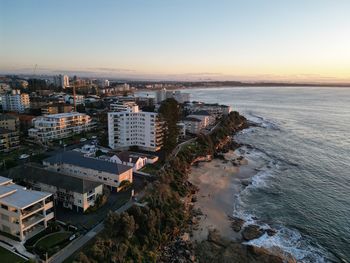 High angle view of townscape by sea against sky during sunset