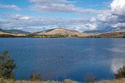 Scenic view of lake by mountains against sky