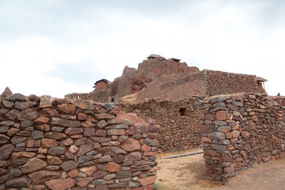 Stone wall with rocks against sky