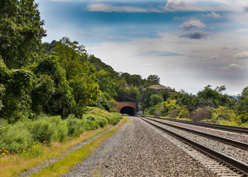 View of railroad tracks by road against sky