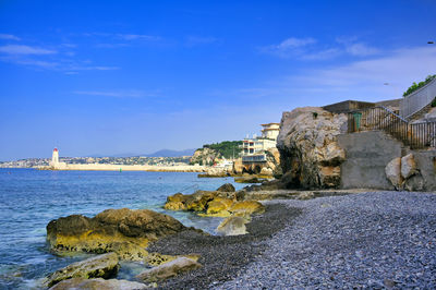 Buildings by sea against blue sky