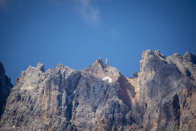 Low angle view of snowcapped mountains against clear blue sky