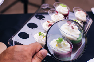 Close-up of cropped hand holding magnifying glass on dessert