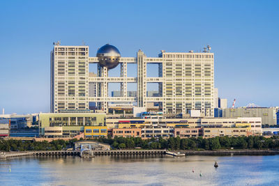 View of buildings by river against sky in city