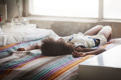 Woman with curly hair lying on bed at home