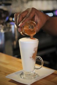 Close-up of hand holding coffee cup on table