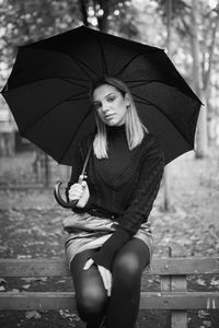 Portrait of beautiful woman holding umbrella during rainy season