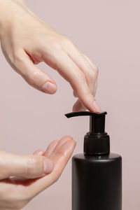 Womens hands press on a black dispenser with a liquid tonic. high quality photo