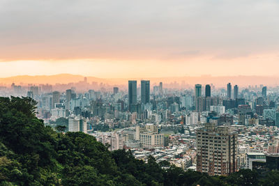 Aerial view of buildings in city against sky during sunset