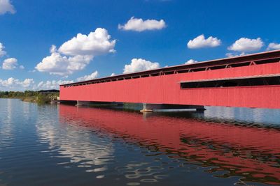 Red house by lake against sky