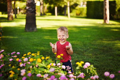 Little boy smiling in the summer in the garden near the flowers