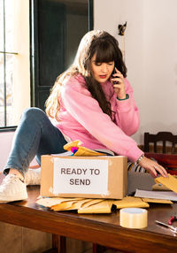 Young woman using digital tablet while sitting on table