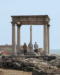 Rear view of man visiting old ruin against sky