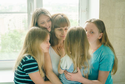 Mother with daughters against window at home