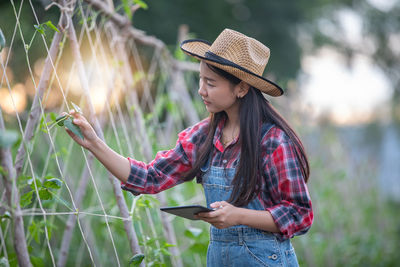 Woman wearing hat while standing on mobile phone outdoors