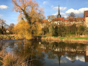 Trees by lake against sky during autumn