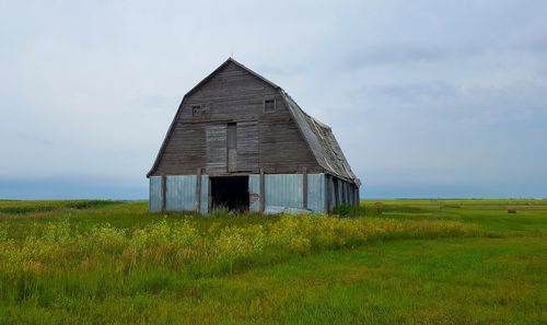 Abandoned barn on field against sky