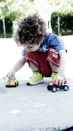 Boy crouching while playing with toy car